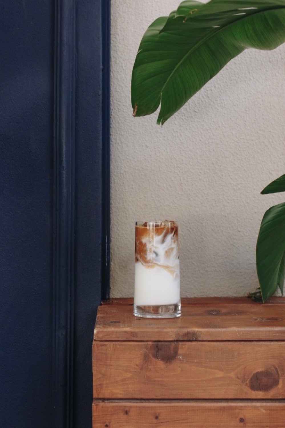 Lacivert cephe önünde ahşap sandık üstünde ice latte