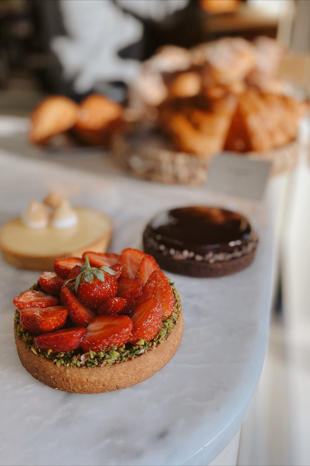 Mermer tezgâhta çilekli, limonlu ve çikolatalı tart yan yana